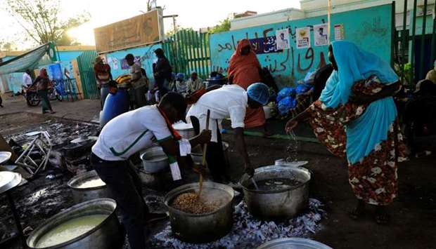 Sudanese volunteers prepare meals for protesters during the Muslim fasting month of Ramadan in front of the defense ministry compound in Khartoum