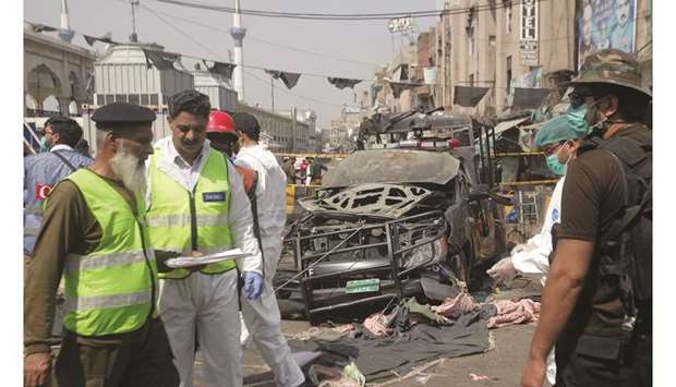 Security officials and members of a bomb disposal team survey the site after a blast in Lahore yesterday.