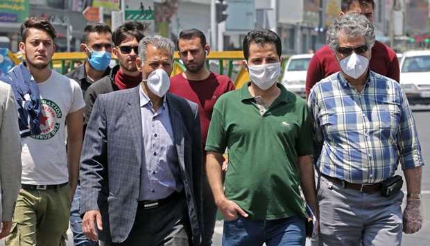 Iranian men, some wearing protective masks amid the novel coronavirus pandemic, walk by on a street of the capital Tehran, yesterday.