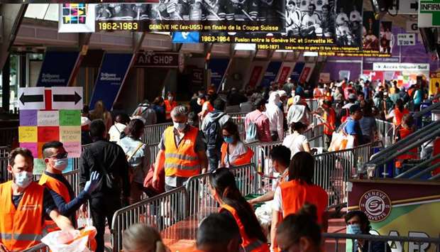 Volunteers distribute bags of donated food and essential products at Genevau2019s Vernets ice rink.