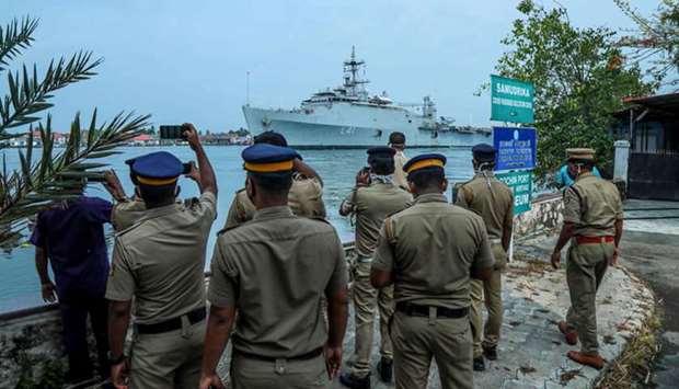 Navy and police personnel watch and take photos as the INS Jalashwa ship enters the Kochi port yesterday.