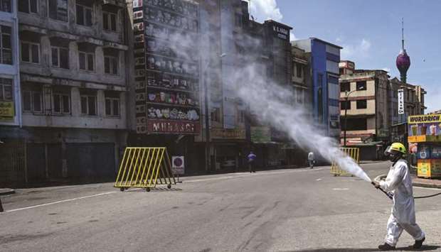 A firefighter wearing protective gear sprays disinfectant to sanitise a road as a preventive measure against the coronavirus a day before the government-imposed nationwide lockdown being eased, in Colombo yesterday.