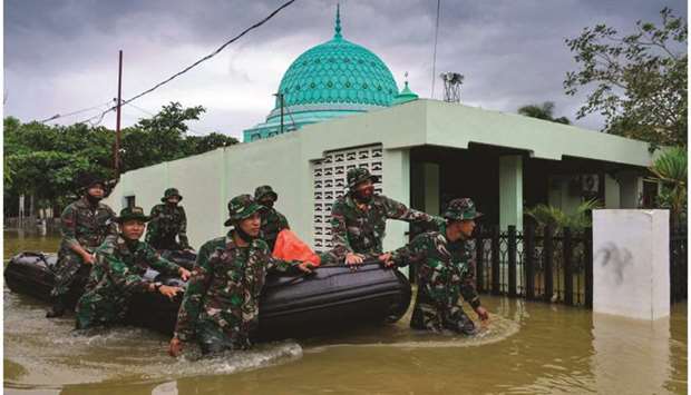 Indonesian soldiers wade through floodwaters with an inflatable raft as they provide assistance to residents following three days of heavy rain in Banda Aceh yesterday.