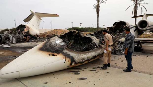 A policeman inspects a passenger plane damaged by shelling at Tripoliu2019s Mitiga airport in Libya yesterday.