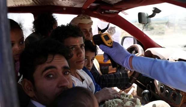 A health worker takes the temperature of people riding a taxi van, amid concerns of the spread of the coronavirus disease, at the main entrance of Sanaa, Yemen