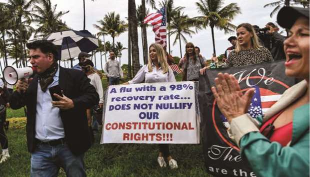 Protestors hold placards, wave US flag and shout slogans, as they participate in a u2018Freedom Rallyu2019 protest in support of opening Florida, in South Beach, Miami, on Sunday.