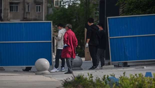 Workers wearing face masks put barriers near a residential compound where five new cases of the coronavirus were detected over the weekend, in Wuhan