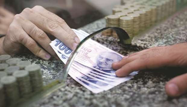 Turkish 100 lira bank notes are exchanged at a currency store counter in this arranged photograph in Istanbul (file). Turkeyu2019s sovereign wealth fund will inject 21bn liras ($3bn) into three state lenders to strengthen their capital positions and minimise the impact of the coronavirus pandemic that may provide a $24bn boost to the market.