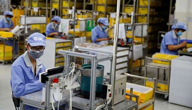Employees wearing face masks work at a factory of the component maker SMC during a government organised tour of its facility following the outbreak of the coronavirus disease, in Beijing