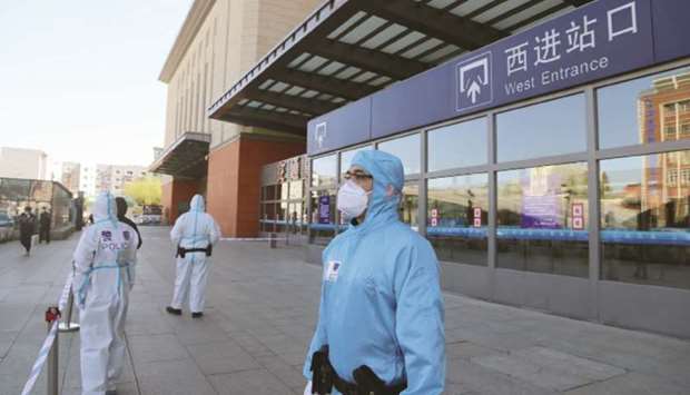 Police officers in protective suits are seen in front a closed entrance to a train station in Jilin, China.
