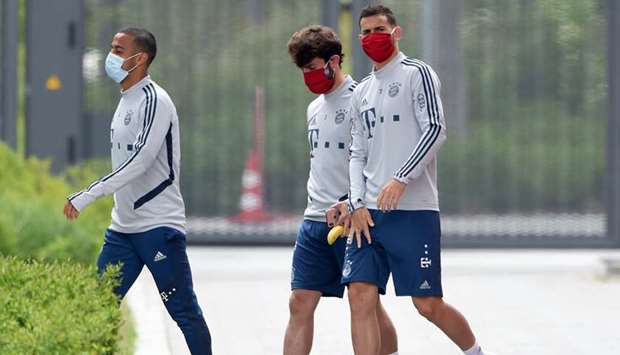 Bayern Munich players Thiago Alcantara (left), Alvaro Odriozola (centre) and Lucas Hernandez wear face masks as they arrive for a training session in Munich. (AFP)