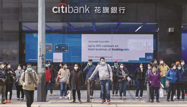 Pedestrians wearing protective masks cross a road in front of a Citibank branch in the Central district of Hong Kong.