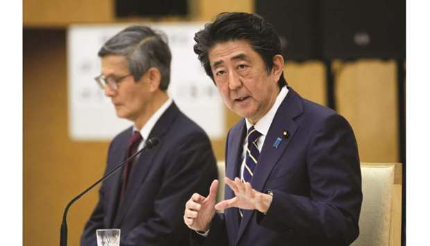 Japanu2019s Prime Minister Shinzo Abe gestures alongside Shigeru Omi, president of the Japan Community Healthcare Organization during a news conference in Tokyo yesterday.