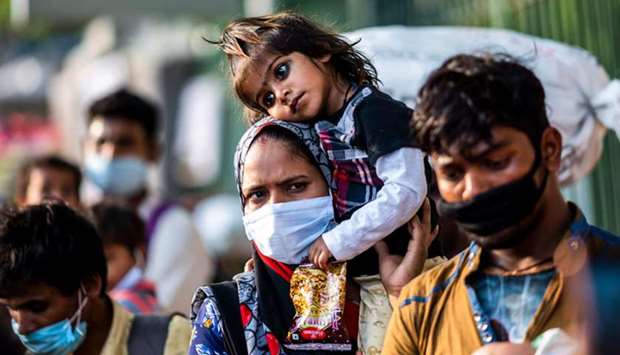 A migrant worker mother carries her daughter on her shoulder as she walks along a street in New Delhi yesterday.