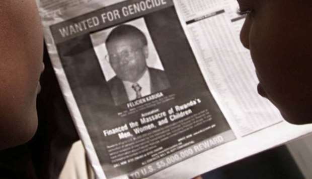 FILE PHOTO: Readers look at a newspaper carrying the photograph of Rwandan Felicien Kabuga