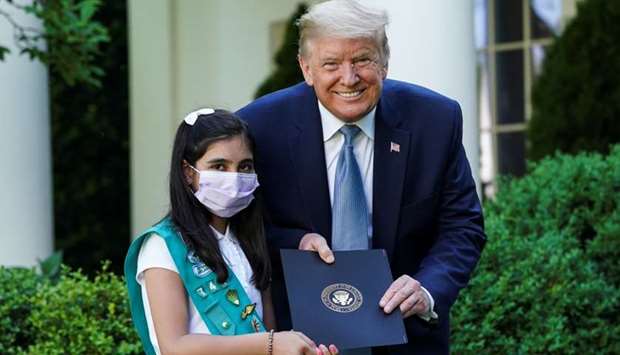 US President Donald Trump poses with girl scout Laila Khan of Troop 744 in Elkridge, Maryland after she was presented with a letter of recognition during a coronavirus disease pandemic response event in the Rose Garden at the White House in Washington.