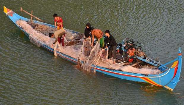 Men pull a fishing net from the Bassac river in Phnom Penh, Cambodia