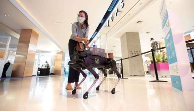 A woman uses a sanitising hand gel from a four-legged dog robot called u2018K9u2019 at the Central World department store in Bangkok