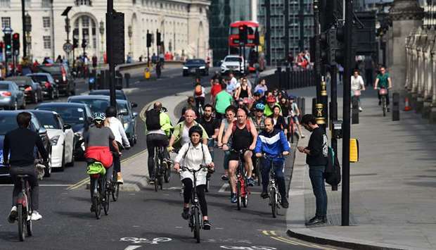 People cycle through Parliament Square in central London yesterday following an easing of lockdown rules in England.