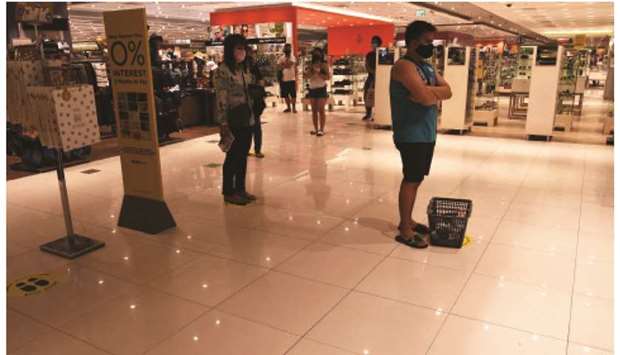 Customers observing social distancing measures while waiting in a queue to pay a cashier at a mall in Manila, yesterday.