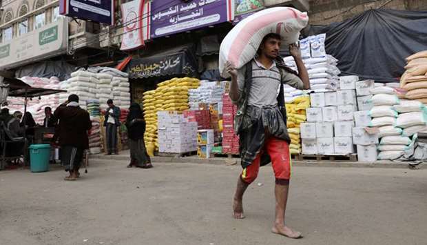 A worker carries a sack of wheat flour outside a food store amid concerns over the spread of the coronavirus disease (Covid-19), in Sanaa, Yemen.