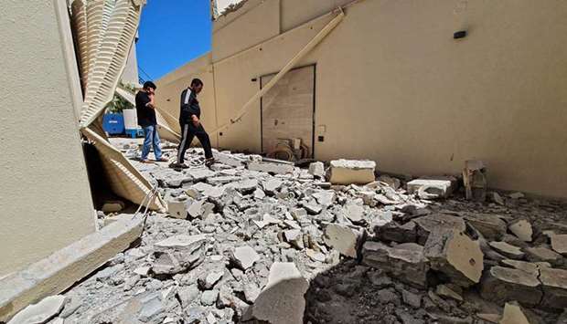 Residents walk amidst the rubble of a building that was damaged when forces loyal to eastern-based strongman Khalifa Haftar shelled the residential neighbourhood of Zenata  in Tripoli, Libya, yesterday.