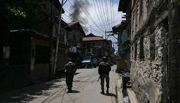 Paramilitary soldiers patrol a street as smoke rises from a house at the site of a gun-battle between suspected militants and government forces in Srinagar yesterday.