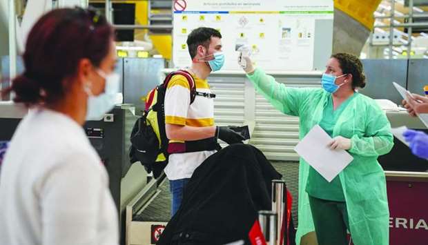 A medical worker checks the temperatures of a passenger at the check-in counters inside the departures terminal at Madrid Barajas airport in Spain. Restarting commercial aviation will require governments to assume broad new responsibilities in terms of assessing and identifying traveller health risks, as governments did for security after 9/11 (terrorist attack in the US), points out International Air Transport Association.