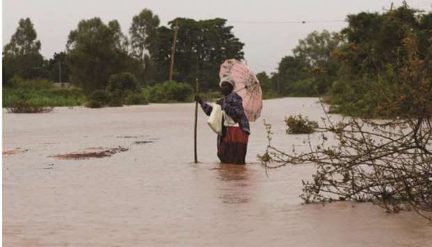 A woman wades through waters after homes were flooded, as River Nzoia burst its banks due to heavy rainfall and the backflow from Lake Victoria, in Budalangi within Busia County, Kenya.