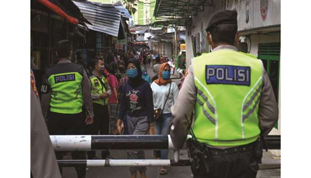 Police look on in a market area as they conduct an operation against clothes vendors defying a partial lockdown against the coronavirus pandemic, in Jakarta yesterday.
