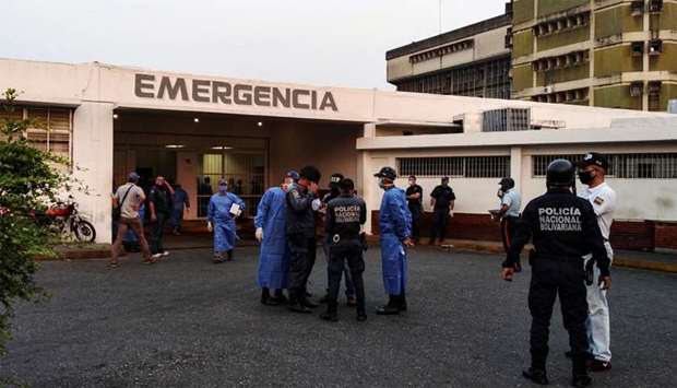 Healthcare workers and members of the Bolivarian national police wait for the arrival of prisoners outside a hospital after a riot erupted inside a prison in Guanare