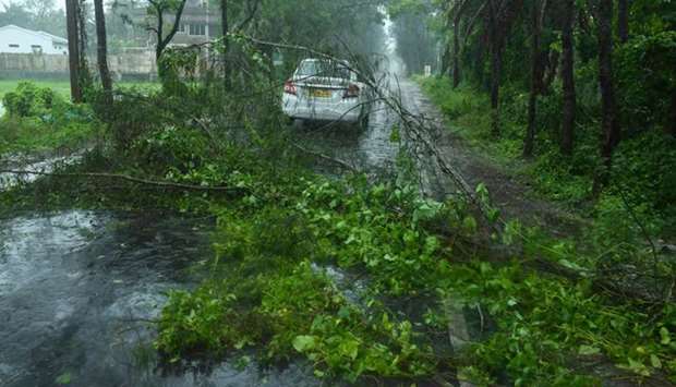 A car drives past fallen tree branches along a road in Digha, West Bengal, yesterday.
