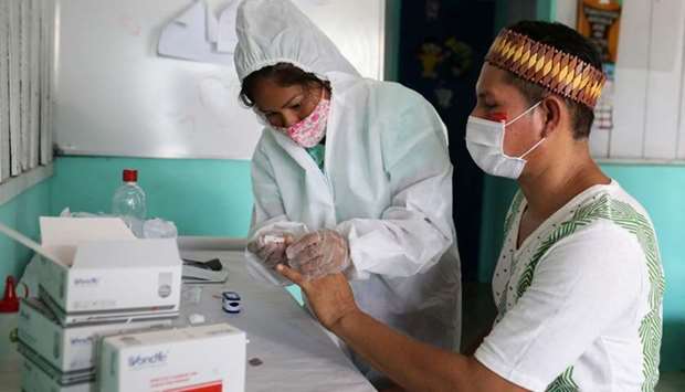 Kambeba indigenous nurse technician Neurilene Cruz, 36, conducts tests for the coronavirus disease on indigenous Tome Cruz, 36, on the banks of the Negro river at the village of Tres Unidos, Amazon state, Brazil