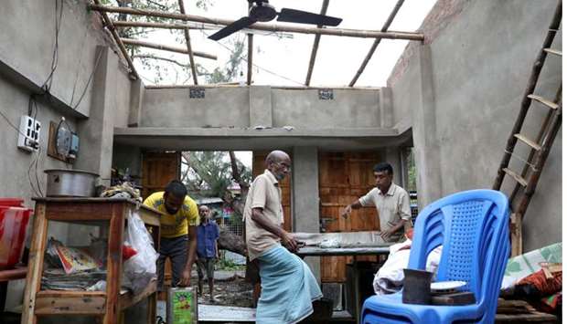 Men salvage items from a damaged shop after Cyclone Amphan made its landfall, in South 24 Parganas district in the eastern state of West Bengal, India,