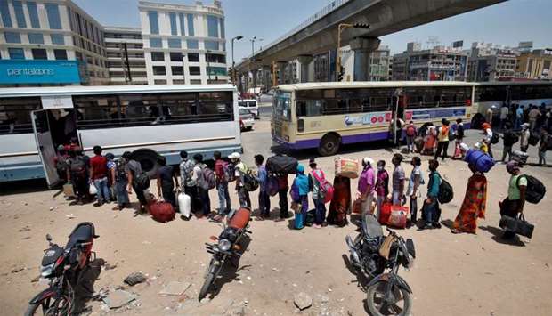 Migrant workers and their families get on buses to reach a railway station to board a train to their home state of eastern Bihar