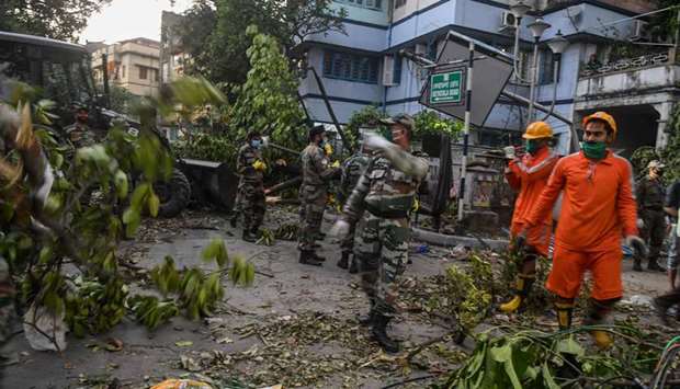 Army personnel along with National Disaster Response Force (NDRF in orange) deploy to clean roads from fallen tree, electric lines and others following the landfall of cyclone Amphan, in Kolkata yesterday.