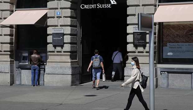 A pedestrian wearing a protective face mask walks past a Credit Suisse Group bank branch in Hong Kong. Global private banks including Credit Suisse and UBS, as well as Asian wealth managers have their regional operations in the Asian financial hub.