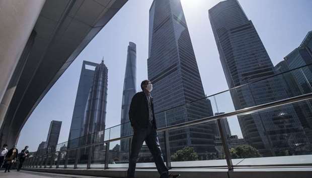 A pedestrian wearing a protective mask walks through the Lujiazui Financial District in Shanghai. Economists surveyed by Bloomberg expect Chinau2019s economy to expand just 1.8% this year, its worst performance since the 1970s.