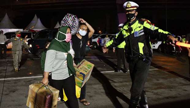 People travelling to their hometown for Eid al-Fitr celebrations marking the end of the Muslim holy month of Ramadan, are told by police (right) to return to Jakarta due to travel bans to prevent the spread of the coronavirus, in Cikarang, West Java, yesterday.