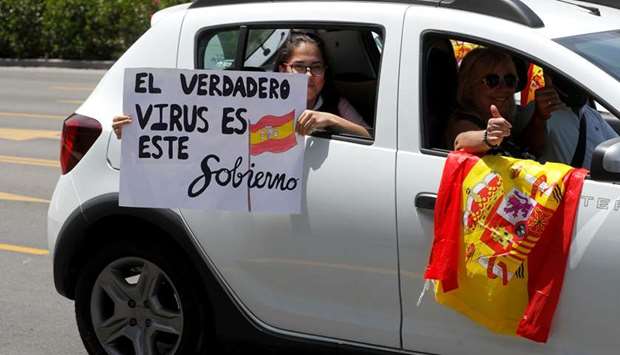 A girl holds a notice reading u2018The real virus is this governmentu2019 during a drive-in protest in Malaga, southern Spain, organised by Spainu2019s far-right party Vox against the governmentu2019s handling of the coronavirus outbreak.