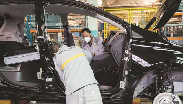Employees wearing protective face masks work on internal fittings on the Nissan Micra hybrid automobile assembly line at the Renault factory in Flins, France.