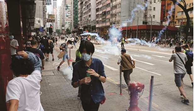 Anti-government protesters react as riot police fire tear gas to disperse them during a march against Beijingu2019s plans to impose national security legislation in Hong Kong yesterday.