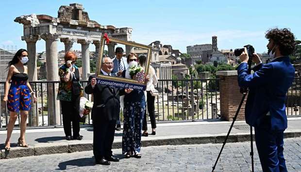 A newly-married couple pose for a picture yesterday in front of the Roman forum in Rome, as the country eases lockdown measures taken to curb the spread of the coronavirus. The text on the photo frame reads u2018Crown(ing) of loveu2019, a play on the Italian word for both u2018crownu2019 and the coronavirus.