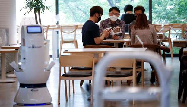 Customers wait at a cafe where a robot that takes orders, makes coffee and brings the drinks straight to customers is being used in Daejeon, South Korea