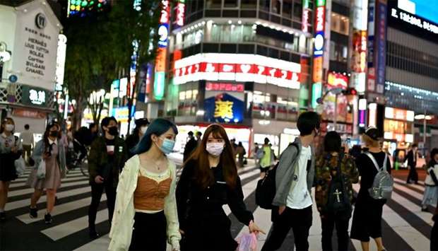 People wearing face masks cross a street in Tokyou2019s Shinjuku area