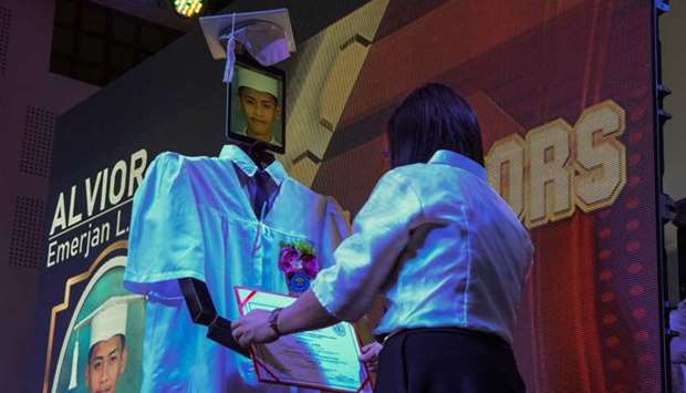 A diploma is attached to a robots, with a graduating student picture shown on a tablet, as the first ,cyber graduation, ceremony from a science and technology college is held due to the ban on mass gatherings during the coronavirus outbreak in Manila  on May 22.