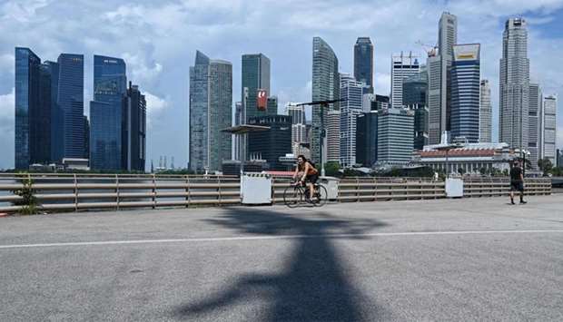 A cyclist rides past buildings in the financial business district (background) in Singapore.