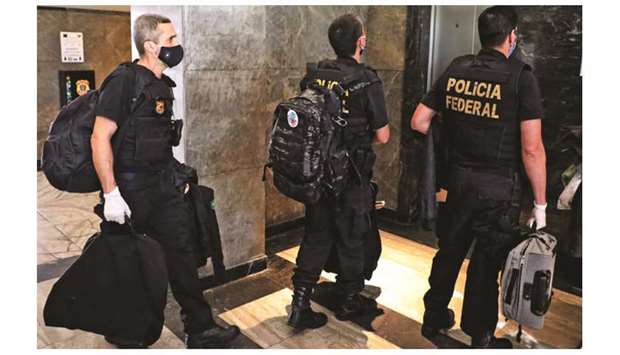 Police officers carrying seized evidence walk into the Federal Police headquarters in Rio de Janeiro, Brazil, yesterday.