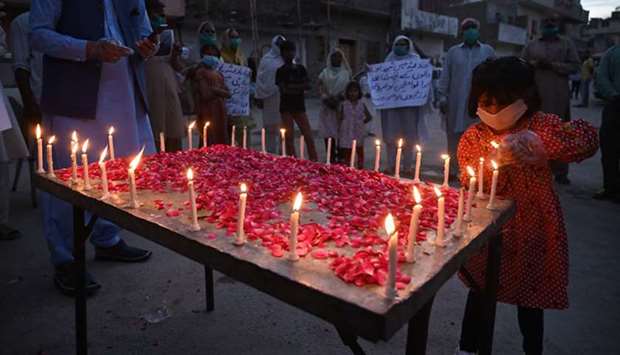A girl lights candle as other carry placards in Islamabad yesterday, during a vigil for the victims of the Pakistan International Airlines (PIA) plane crash in Karachi on May 22.
