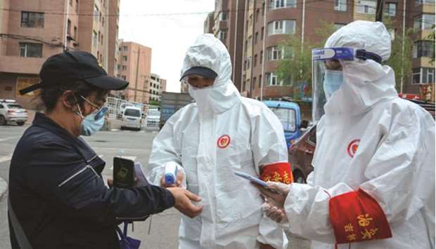 Volunteers wearing protective clothing, amid concerns of the Covid-19 coronavirus, checking the body temperature of a resident outside a residential area in Jilin in Chinau2019s northeastern Jilin province yesterday.